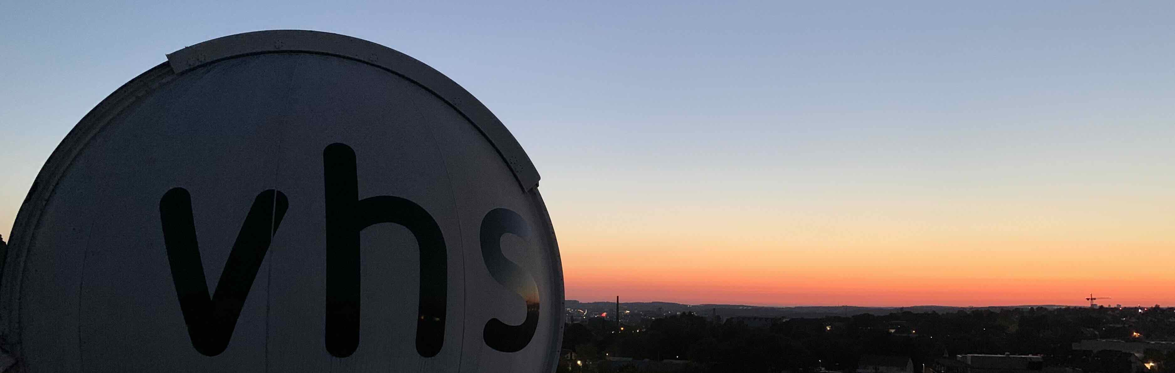 Die Kuppel der Sternwarte Reutlingen mit vhs-Schriftzug vor dem Abendhimmel